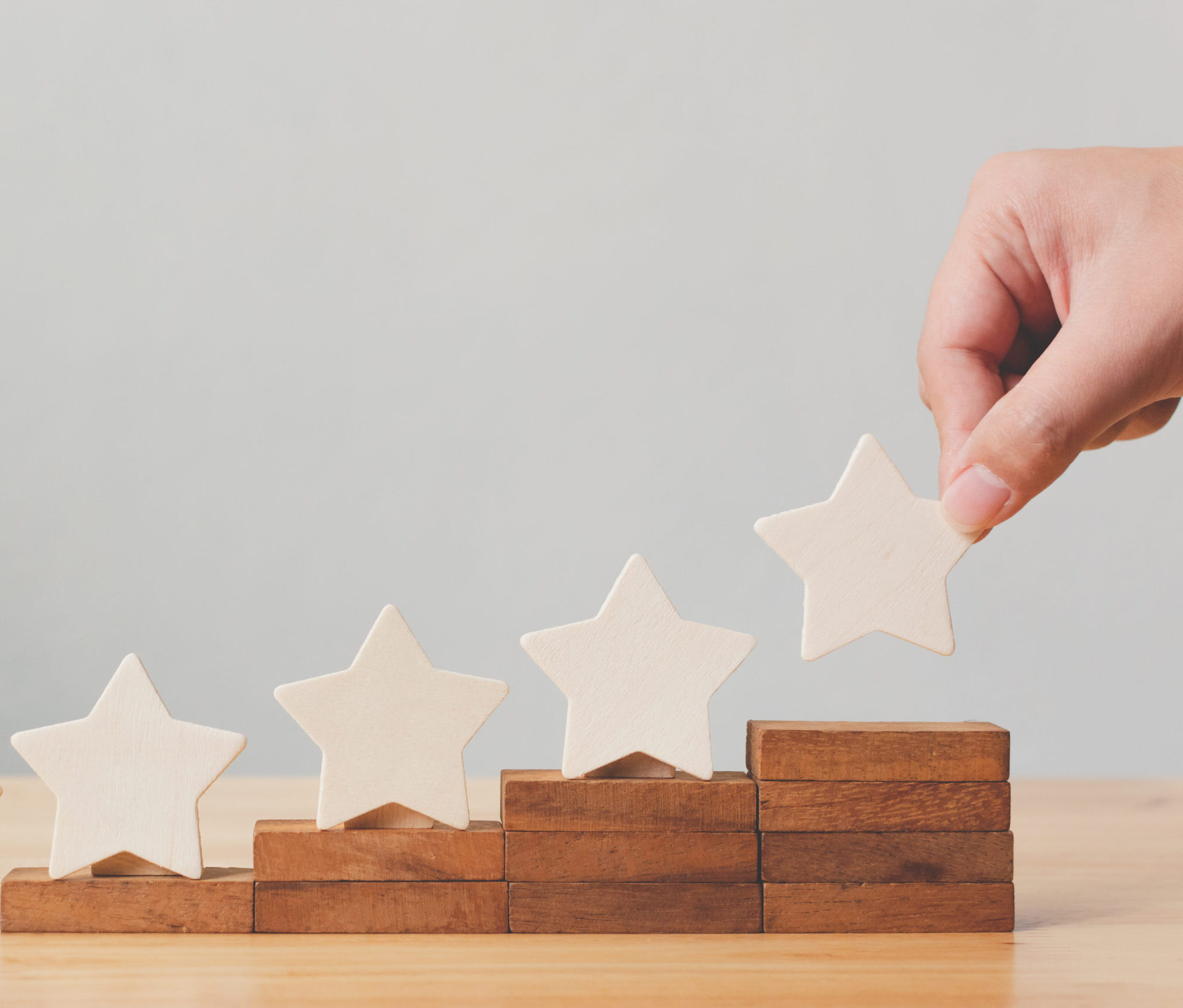 Hand putting wooden five star shape on table. The best excellent business services rating customer experience concept
